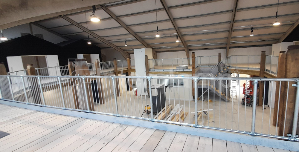 Close-up of Interclamp pedestrian barriers and tube clamp fittings forming a secure guardrail system for fall protection on a second-floor mezzanine, enhancing indoor safety.